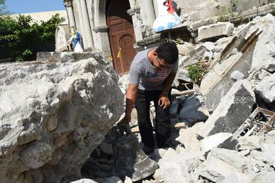 A church worker inspects a bell from the 18th century St. Catherine of Alexandria after its bell tower was destroyed.A FP