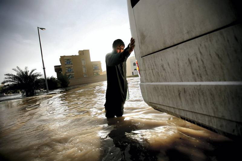 December 13, 2009 / Abu Dhabi / (Rich-Joseph Facun / The National) A man helps a bus driver push his vehicle through a flooded street in Al Bateen after it stalled during the storm, Sunday, December 13, 2009 in Abu Dhabi.  *** Local Caption ***  rjf-1213-rain009.jpg
