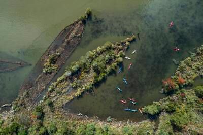 An image made with a drone shows kayakers paddling by the wooden hulls of sunken ships, many from WW1, in the Mallows Bay-Potomac River National Marine Sanctuary near Nanjemoy, Maryland, USA, 30 September 2023.  Known as the 'Ghost Fleet of the Potomac,' the boats were beached and burned after the war.   EPA / JIM LO SCALZO