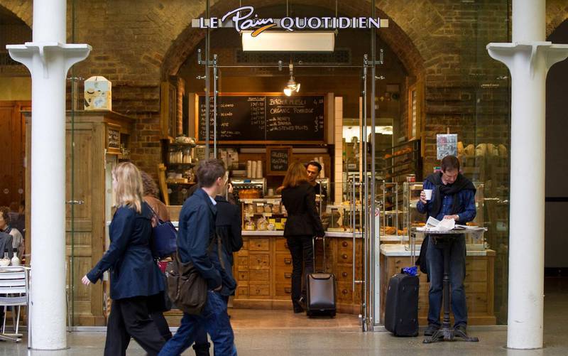 Travelers are seen outside Le Pain Quotidien continental-style boulangerie and patisserie, at St Pancras International railway station in London, U.K., on Monday, Sept. 26, 2011. German bratwurst and Hugo Boss suits are set to vie with croissants, camembert and other French staples in shops at London's Channel Tunnel terminus as the station prepares for direct trains from Cologne and Frankfurt. Photographer: Simon Dawson/Bloomberg