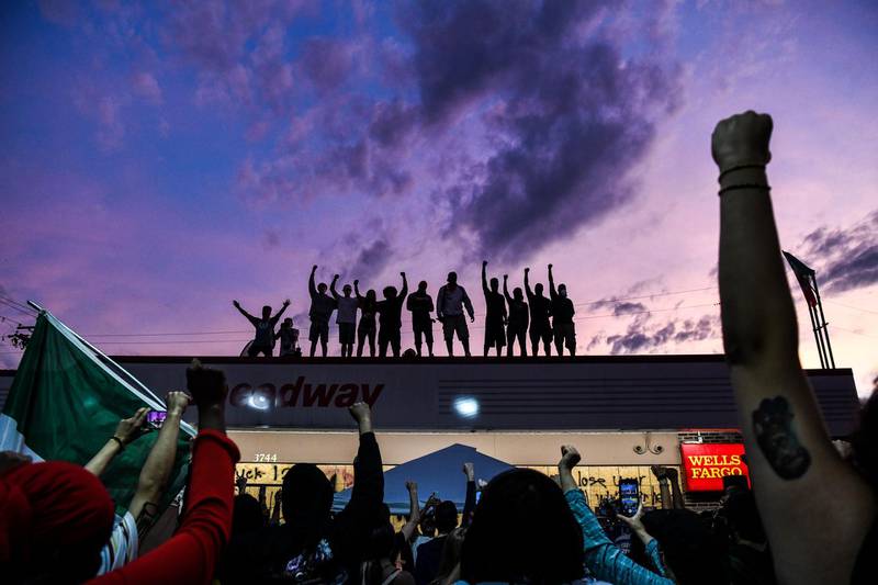 People raise their hands as they protest against racism and police brutality at the makeshift memorial in honour of George Floyd in Minneapolis, Minnesota. AFP