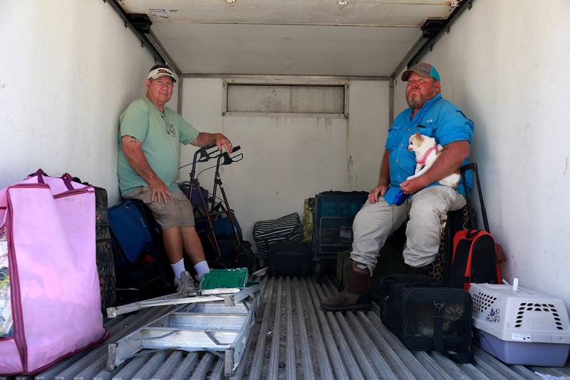 Charlie Russell and Brian Lewis and pup ride in the back of a lorry to a boat off Pine Island. Getty / AFP