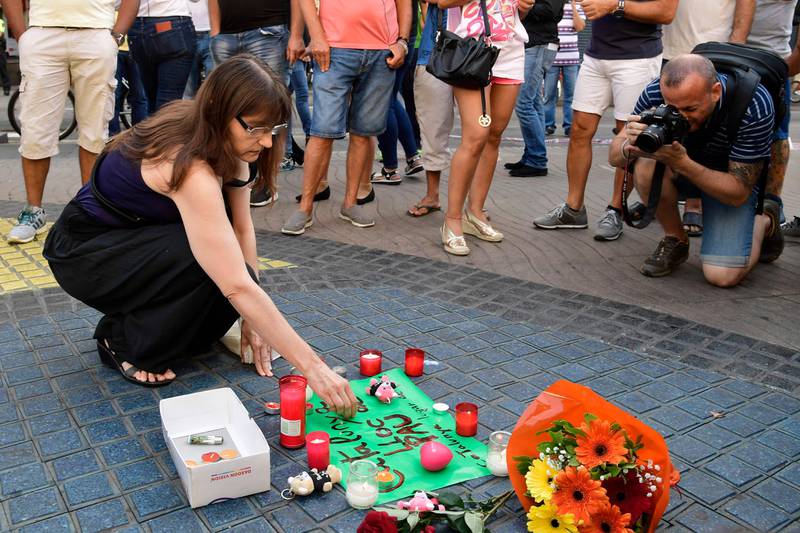A woman displays a candle next to first flowers and a message to the victims on August 18, 2017 on the spot where yesterday a van ploughed into the crowd, killing 13 persons and injuring over 100 on the Rambla boulevard in Barcelona.
Drivers have ploughed on August 17, 2017 into pedestrians in two quick-succession, separate attacks in Barcelona and another popular Spanish seaside city, leaving 13 people dead and injuring more than 100 others. In the first incident, which was claimed by the Islamic State group, a white van sped into a street packed full of tourists in central Barcelona on Thursday afternoon, knocking people out of the way and killing 13 in a scene of chaos and horror. Some eight hours later in Cambrils, a city 120 kilometres south of Barcelona, an Audi A3 car rammed into pedestrians, injuring six civilians -- one of them critical -- and a police officer, authorities said. / AFP PHOTO / JAVIER SORIANO