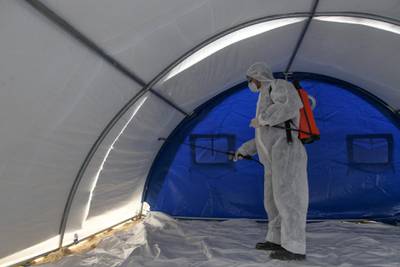 A member of the Syrian Violet NGO disinfects a triage tent erected for suspected coronavirus patients outside the Ibn Sina Hospital in Syria's northwestern Idlib city on March 19, 2020. - Syrian authorities on March 13 announced measures aimed at preventing coronavirus from reaching the war-torn country, including school closures and a ban on smoking shisha in cafes, state media reported. (Photo by Abdulaziz KETAZ / AFP)