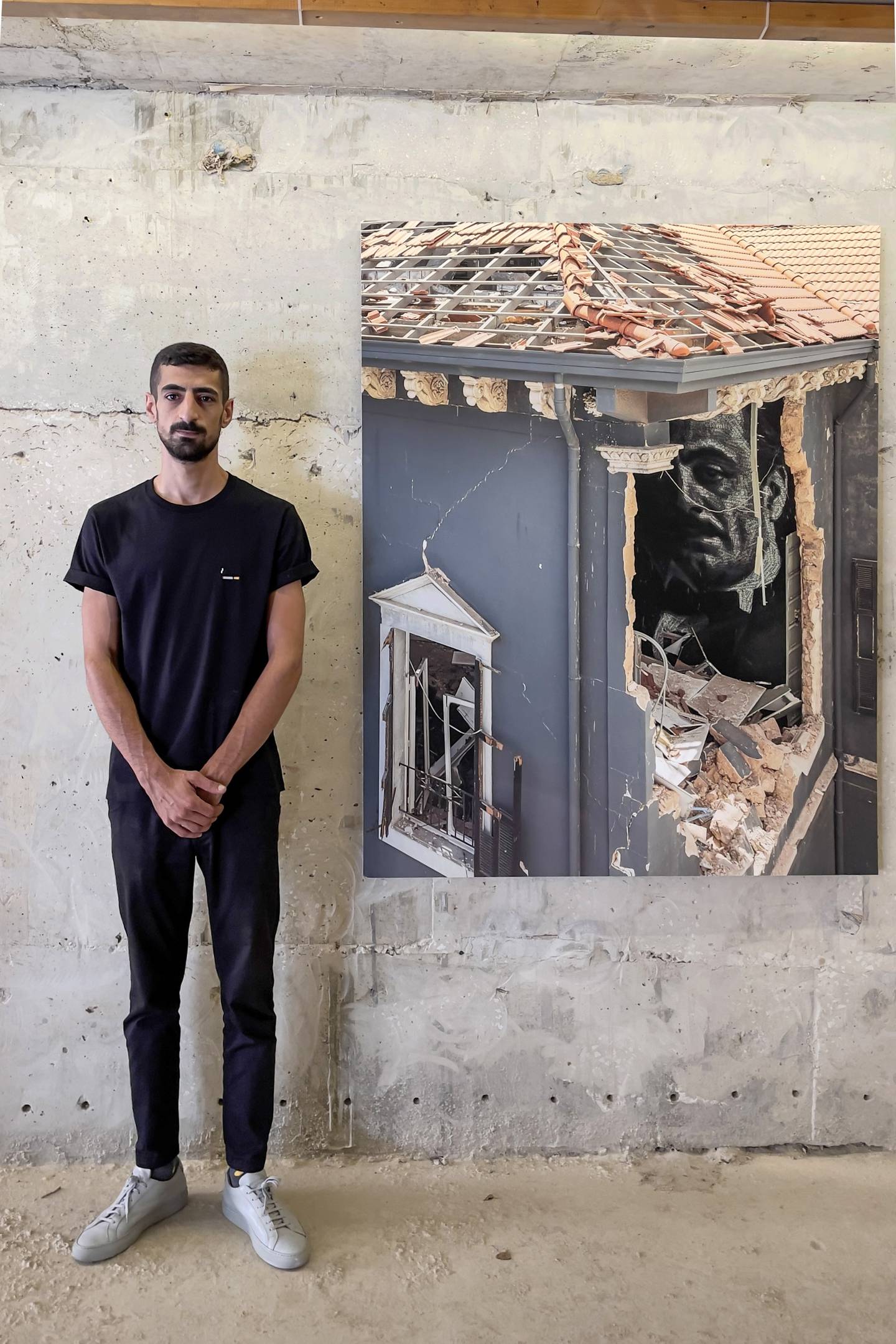 Photographer Dia Mrad next to his image of a mural of Khalil Gibran that was peeking out of a battered house. Courtesy of the artist