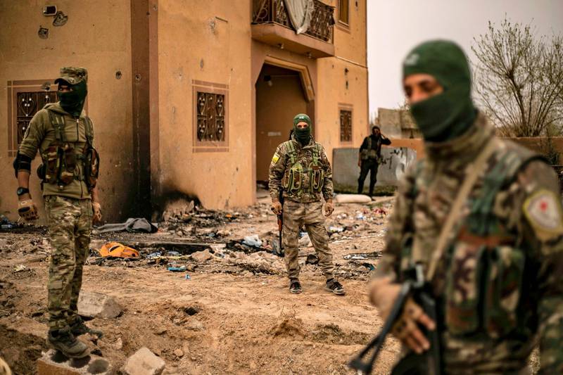 EDITORS NOTE: Graphic content / TOPSHOT - Members of the Syrian Democratic Forces (SDF) walk in the village of Baghouz in Syria's eastern Deir Ezzor province near the Iraqi border on March 24, 2019, a day after the Islamic State (IS) group's "caliphate" was declared defeated by the US-backed Kurdish-led SDF.  / AFP / Delil souleiman
