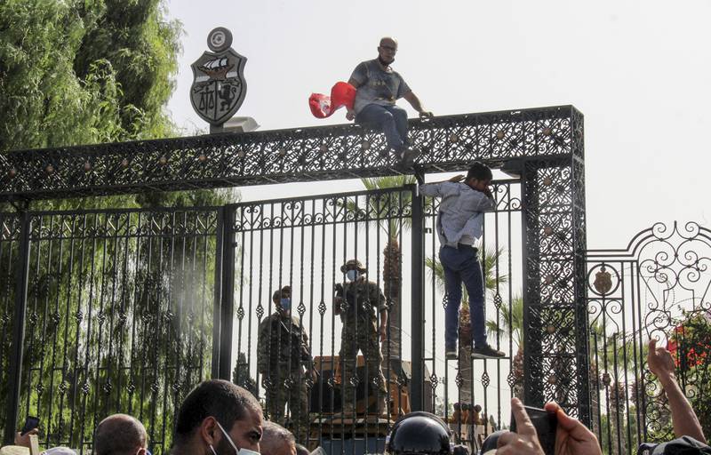 Security forces guard the main entrance of the Tunisian Parliament in the capital Tunis, as  demonstrators scale the gates, after President Kais Saied suspended the legislature. AP