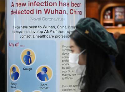 A woman wearing a face mask passes a health notice warning passengers arriving at London's Heathrow Airport about the virus.  AFP