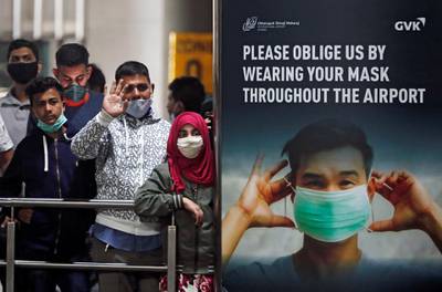 People wearing protective face masks wait for passengers to arrive at Chhatrapati Shivaji Maharaj International Airport after India cancelled all flights from the UK over fears of a new strain of the disease, in Mumbai, India. Reuters