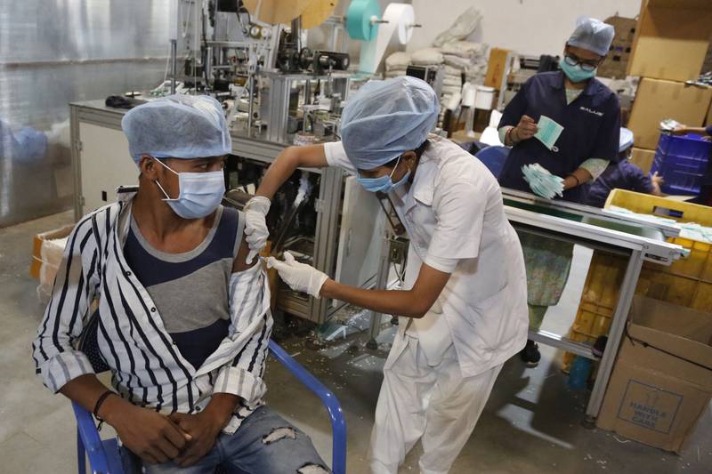 A health worker administers the Covishield vaccine for Covid-19 to a worker at the factory of a face mask manufacturer on the outskirts of Ahmedabad, India. AP