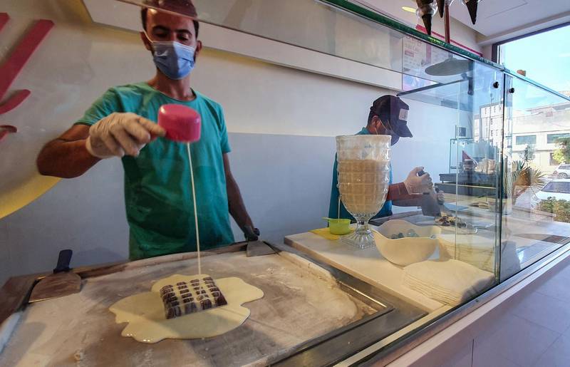 Employees prepare rolled ice cream for customers at a shop in the Libyan capital Tripoli on September 20, 2020. AFP