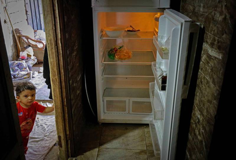 A Lebanese child stands next to an empty refrigerator in their apartment in the port city of Tripoli. AFP
