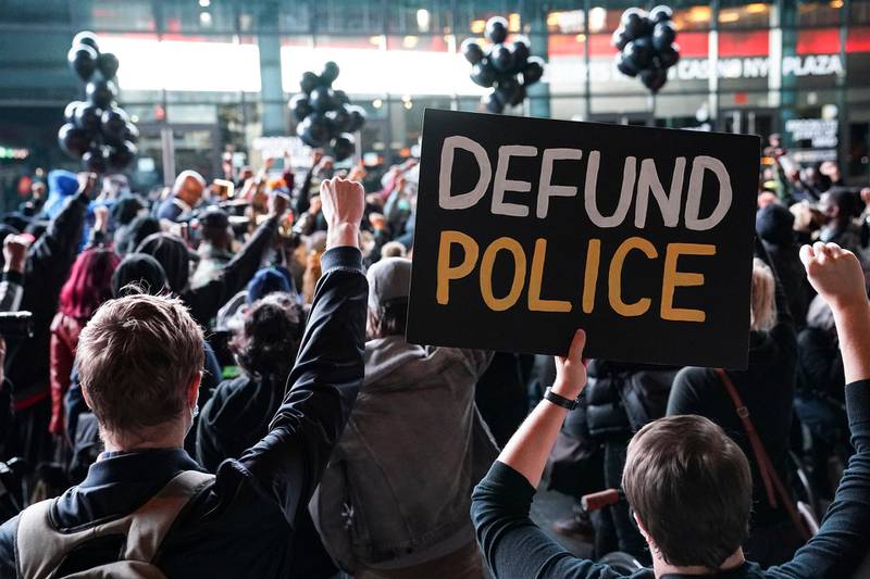 FILE - In this Wednesday, Oct. 14, 2020, file photo, a protester holds a sign that reads "Defund Police" during a rally for the late George Floyd outside Barclays Center, in New York. Demonstrators gathered on what would have been Floyd's 47th birthday to call for action in correcting systemic racism in policing and for criminal justice reform. Responses to the coronavirus pandemic and police brutality dominated legislative sessions in 2020 and led to many new laws that will take effect in the new year. (AP Photo/John Minchillo, File)