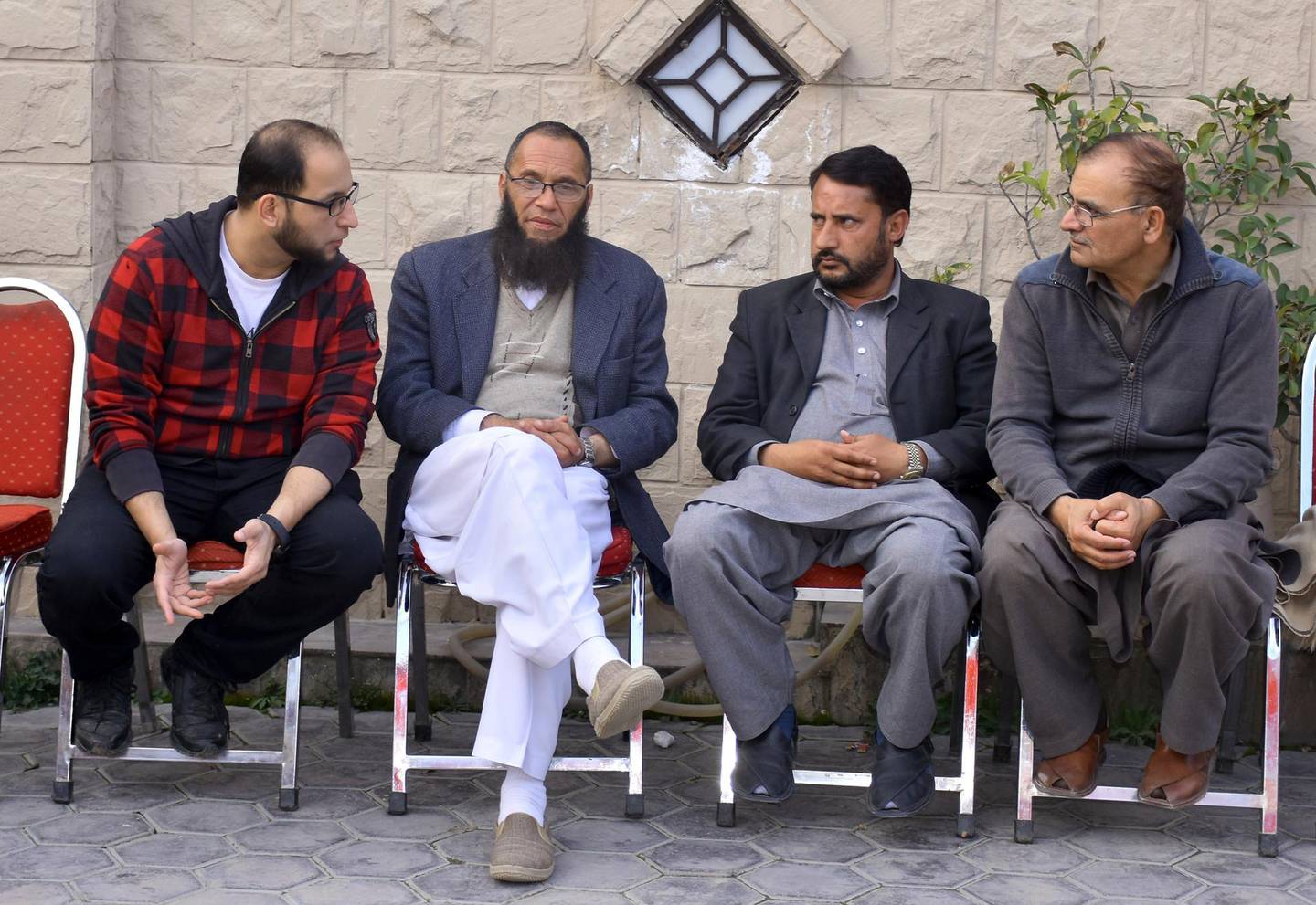 Relatives talk to Nadeem Rashid, second left, bother of a Pakistani citizen Rashid Naeem, who was reportedly killed along with and his son Talha Naeem in the Christchurch mosque shooting, at their home in Abbottabad, Pakistan, Saturday, March 16, 2019. Pakistan's foreign minister says nine Pakistanis were missing after the mass shootings at two mosques in the New Zealand city of Christchurch. (AP Photo/Aqeel Ahmed)