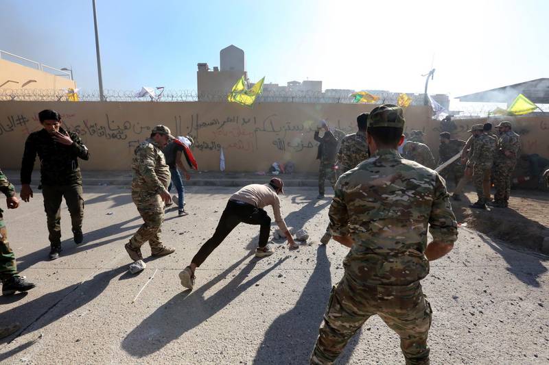 Members of the Iraqi Popular Mobilisation Forces, which is comprised of some Iran-backed militias, and their supporters throw stones as they attack the US embassy during a protest in Baghdad.  EPA