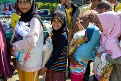 Thai Muslim girls carry bags of rice and food donated by the local government during a ceremony ahead of the Islamic holy month of Ramadan in the southern Thai province of Narathiwat. AFP