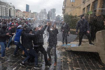 BEIRUT, LEBANON - FEBRUARY 11: Anti-government protesters are hit by a water cannon as they pull down a concrete barricade during a failed attempt to block politicians from accessing Parliament where they will vote whether to accept Lebanon's new government, on February 11, 2020 in Beirut, Lebanon. (Photo by Sam Tarling/Getty Images)