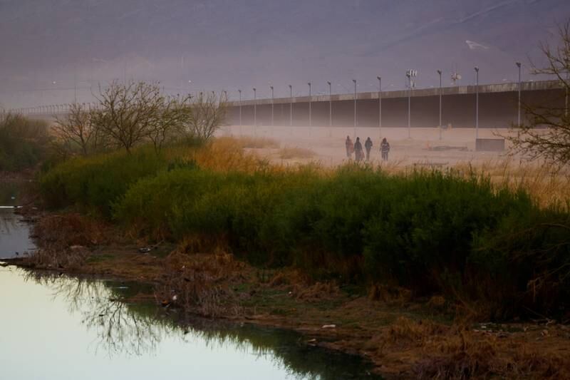 Migrants walk along the border wall after crossing the Rio Bravo in Mexico with an intention to surrender to the US border patrol agents. Reuters