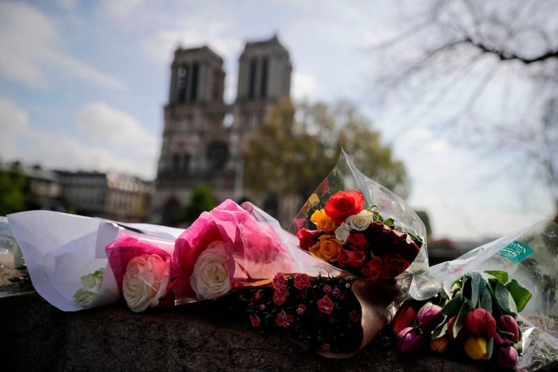 Flowers are laid on a bridge in front of the Notre-Dame-de Paris Cathedral in Paris on April 17, 2019, two days after a fire that devastated the building in the centre of the French capital.  French President vowed on April 16 to rebuild Notre-Dame cathedral "within five years", after a fire which caused major damage to the 850-year-old Paris landmark. / AFP / Thomas SAMSON
