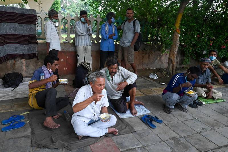 Homeless people eat food being distributed by volunteers along the roadside in New Delhi. AFP