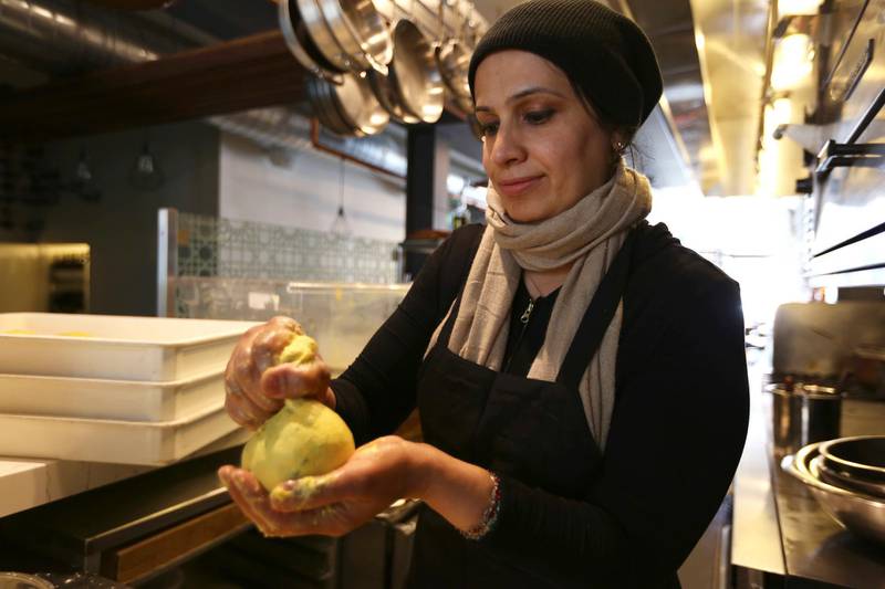In this photo taken June 20, 2018, Muna Anaee, prepares a ball of khobz orouk, a flatbread she would eat frequently in her native Iraq, at the Tawla restaurant kitchen in San Francisco during the inaugural Refugee Food Festival. San Francisco restaurants are opening their kitchens for the first time to refugees who are showcasing their culinary skills and native cuisines while raising their profiles as aspiring chefs as part of a program to increase awareness about the plight of refugees worldwide. (AP Photo/Lorin Eleni Gill)