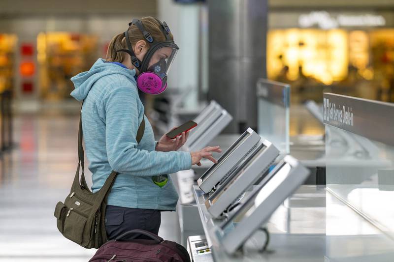 A traveler wearing a respirator uses an automated check-in kiosk at San Francisco International Airport (SFO) in San Francisco, California, U.S., on Monday, Nov. 24, 2020. Airlines set a new post-pandemic record for U.S. passengers on Sunday as the Thanksgiving holiday spurred travel despite government warnings. Photographer: David Paul Morris/Bloomberg