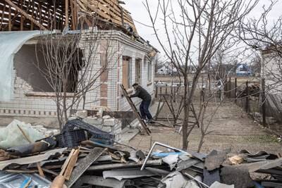 A man climbs up a ladder to examine his destroyed house in the village of Krasylivka outside Kyiv. Reuters