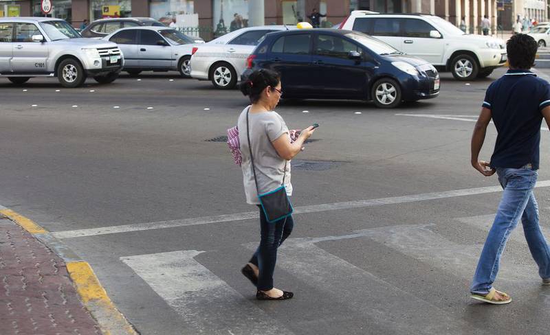 A woman puts herself at risk by crossing at the junction of Electra Street and Muroor Road, in Abu Dhabi city, while texting. Lee Hoagland / The National