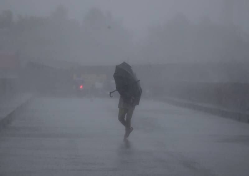A villager braves strong winds on a road in Bacoor city, Cavite. EPA