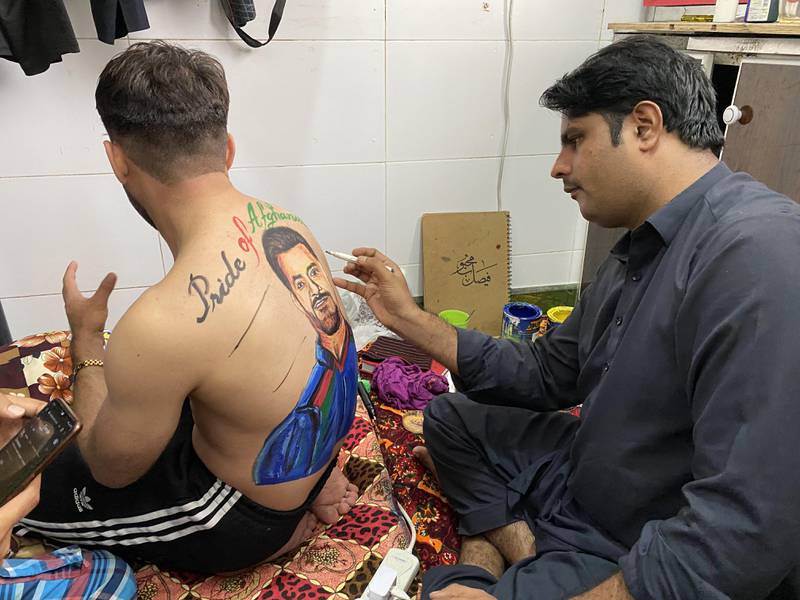 Faisal Mahboob paints Afghanistan superfan Rahim Sediqi's back at his apartment in Hor Al Anz. Paul Radley / The National