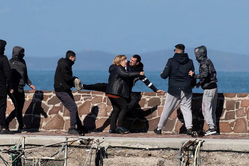 Locals, who prevent migrants on a dinghy from disembarking at the port of Thermi, beat a journalist, as a woman tries to stop them, on the island of Lesbos, Greece. REUTERS
