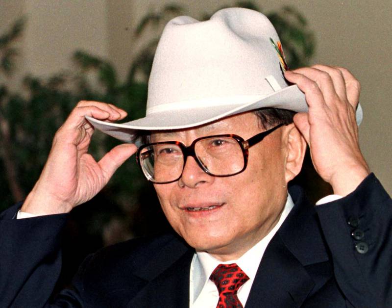 Jiang Zemin tries on a cowboy hat given to him by the mayor of Calgary, Al Duerr, in Canada, November 26, 1997. Reuters
