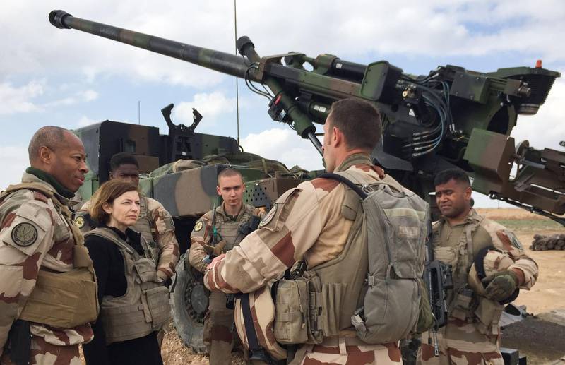 French General Jean-Marc Vigilant (L) and French Defence Minister Florence Parly (2nd L) talk to French soldiers engaged in the "Operation Chammal", the French military operation within "Operation Inherent Resolve", the international coalition against the Islamic State (IS) group, as they stand in front of a wheeled 155 mm gun-howitzer CAESAR system (truck equipped with an artillery system) on February 9, 2019, near Al-Qaim, a few kilometres away from the last scrap of territory held by IS in eastern Syria. The US-backed Syrian Democratic Forces said on February 9, 2019 it had begun the "final battle" to oust the Islamic State group from the last scrap of territory it holds in eastern Syria. / AFP / Daphné BENOIT
