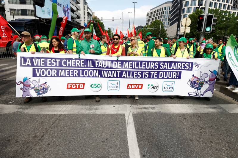 A banner is unfurled as people in Brussels protest over the rising cost of living, with the message 'Life is expensive, we need better wages'. Reuters