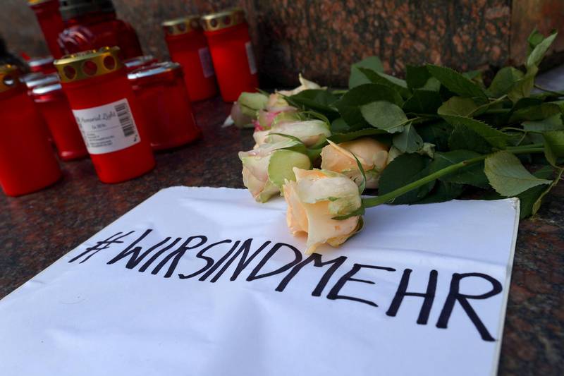 Candles and flowers are seen placed at the Brothers Grimm monument for the victims of a shooting in Hanau, near Frankfurt, Germany. The sign reads "We are more". Reuters