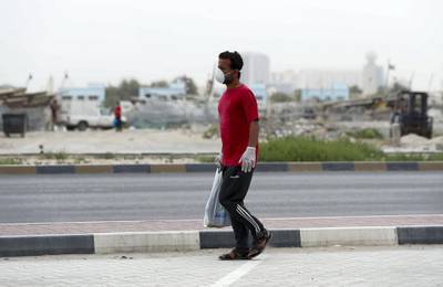 Ajman, United Arab Emirates - Reporter: N/A: A man walks passed fishing boats while wearing a facemask due to the Corona outbreak. Monday, April 13th, 2020. Ajman. Chris Whiteoak / The National