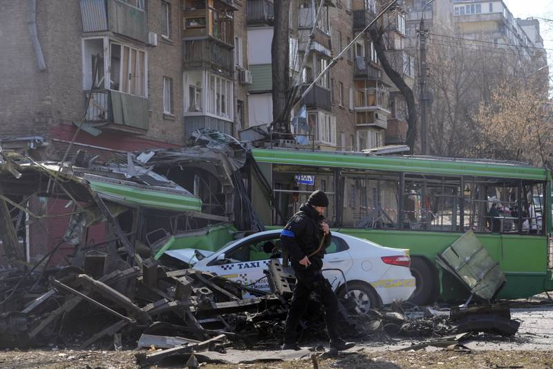 A Ukrainian soldier passes a destroyed a trolleybus and taxi after a Russian bombing attack in Kyiv, Ukraine. AP
