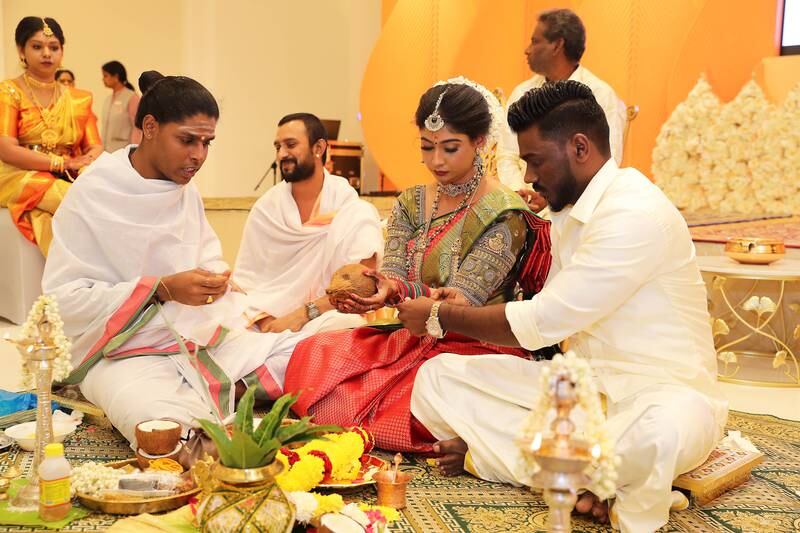 Iswarya Sundararajan and Arvindh Selvam listen as the priest explains the rituals during their wedding ceremony at the Hindu temple in Jebel Ali, Dubai. Pawan Singh / The National 