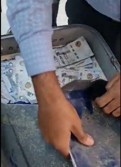 A customs officer tears open a hidden compartment of a suitcase to find a large amount of undeclared currency in Saudi riyals and UAE dirhams. The passenger, who landed in Delhi on a flight from Dubai, was detained. Photo: Delhi Customs
