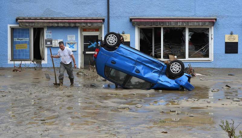 An inhabitant stands by a damaged car at a flooded residential area after heavy rain hit Simbach am Inn, southern Germany. Five persons were found dead in Germany after heavy rains lashed parts of the country, cutting roads, stranding people on rooftops and forcing schools to close their doors. Christof Stache / AFP