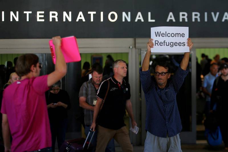 FILE PHOTO: Retired engineer John Wider, 59, is greeted by a supporter of U.S. President Donald Trump as he holds up a sign reading "Welcome Refugees" at the international arrivals terminal at Los Angeles International Airport in Los Angeles, California, U.S. on June 29, 2017.  REUTERS/Mike Blake/File Photo
