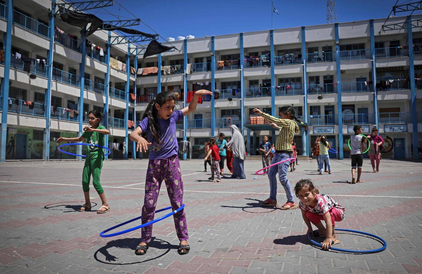 TOPSHOT - Children play at a school run by the United Nations Relief and Works Agency for Palestinian Refugees (UNRWA) where many displaced Palestinian families have sought refuge in Gaza City amid daily air strikes and bombardment by Israeli forces, on May 19, 2021. UNRWA spokesman Adnan Abou Hasna told AFP its schools that have been transformed into shelters for more than 40,000 displaced Gazans could become new coronavirus "epicentres." He said the agency had set up hand-washing stations and other sanitary facilities but conceded these measures were inadequate given the conditions.
 / AFP / MAHMUD HAMS
