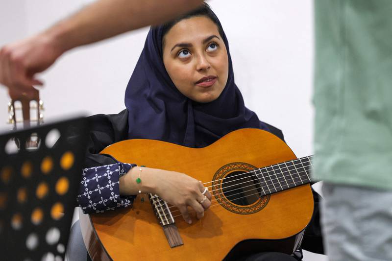 Wejdan Hajji, a 28-year-old employee at a firm selling medical supplies, attends a guitar class at the Yamaha Music Centre in Saudia Arabia's capital Riyadh on June 11, 2022.  - Saudi Arabia's rulers have recently relaxed some social restrictions after decades of adhering to a rigid interpretation of Islam, enforced by the kingdom's religious police and placing severe limits on social activities including group musical lesson.  (Photo by Fayez Nureldine  /  AFP)