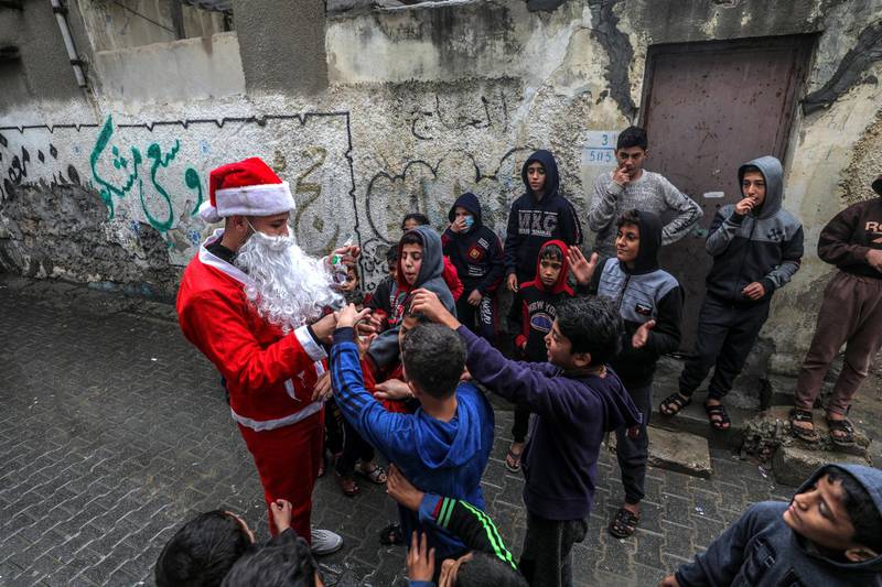 A Palestinian man dressed in a Santa Claus costume spreads happiness among the camp children amid the ongoing coronavirus COVID-19 pandemic, in Al Shatea refugee camp in Gaza City. EPA