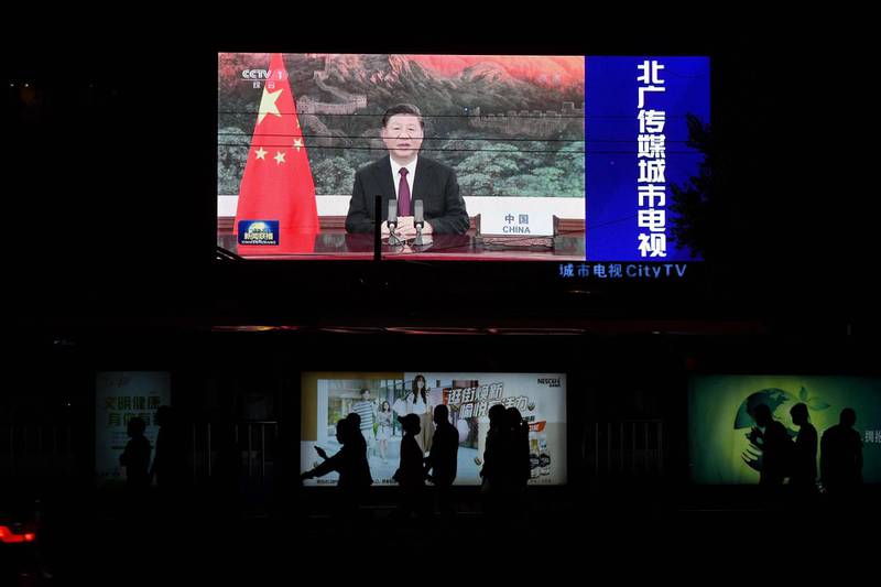 Chinese President Xi Jinping appearing by video link at the United Nations 75th anniversary is seen on an outdoor screen as pedestrians walk past below in Beijing on September 22, 2020. AFP
