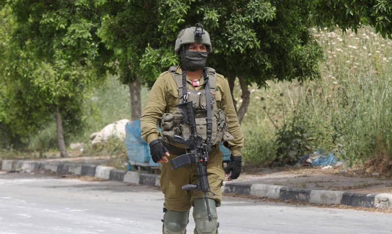 An Israeli soldier guards the main entrance to Azzun village in the West Bank. EPA
