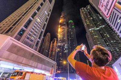 DUBAI. UNITED ARAB EMIRATES, 04 AUGUST 2017. A massive fire rips through The Marina Torch tower's southern corner. One of the many onlookers take a mobile phone picture. (Photo: Antonie Robertson) Journalist: None. Section: National.