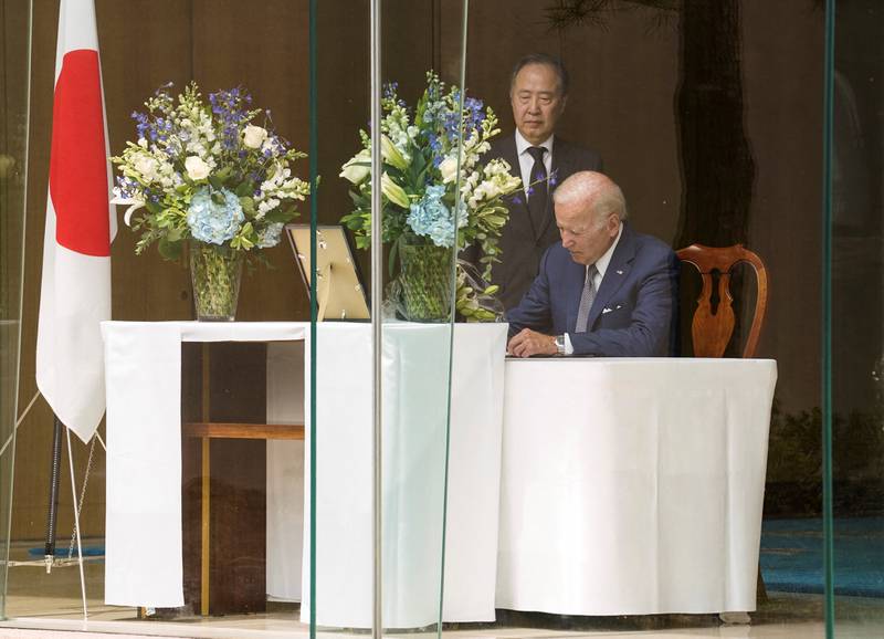 Mr Biden signs a book of condolence. Reuters 