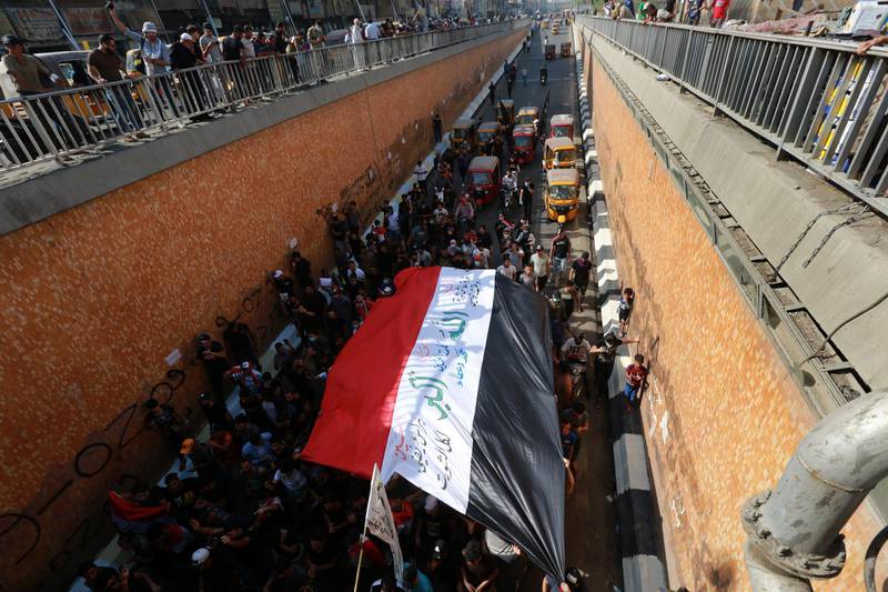 Iraqis carry the Iraqi national flag and chant slogans during a demonstration at Tahrir square in central Baghdad. EPA
