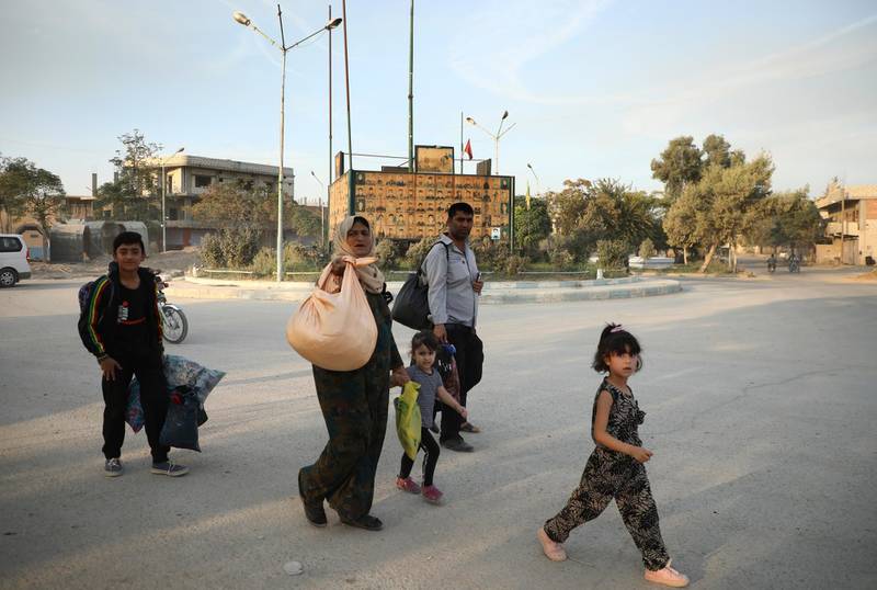In this photo provided by Rojava Media Center, a pro-Kurdish media group, Syrians carry their belongings, as they flee Ras al Ayn, in northeast Syria.  AP